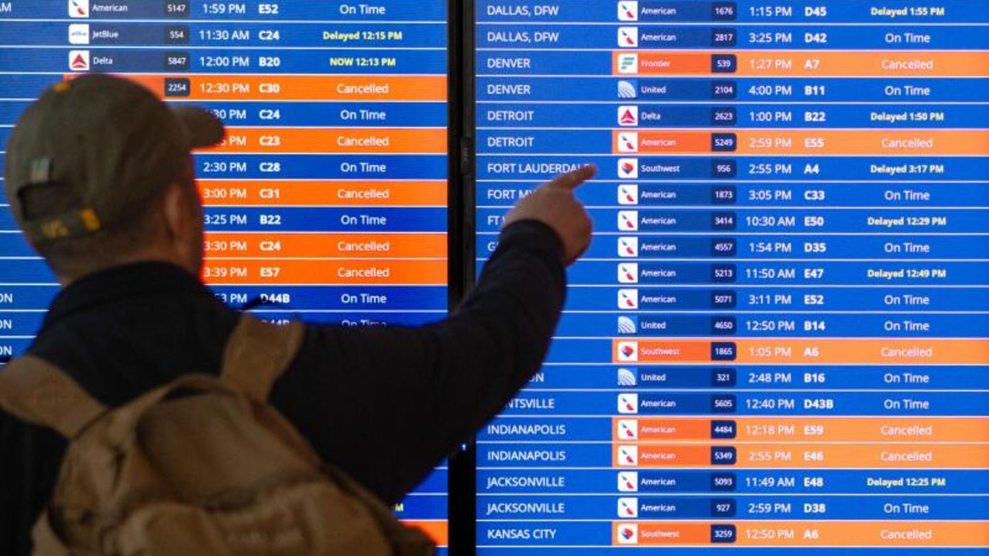 Über 16.000 Flüge storniert Hier steht ein Mann vor einer Informationstafel am Reagan National Airport in Arlington, Virginia
