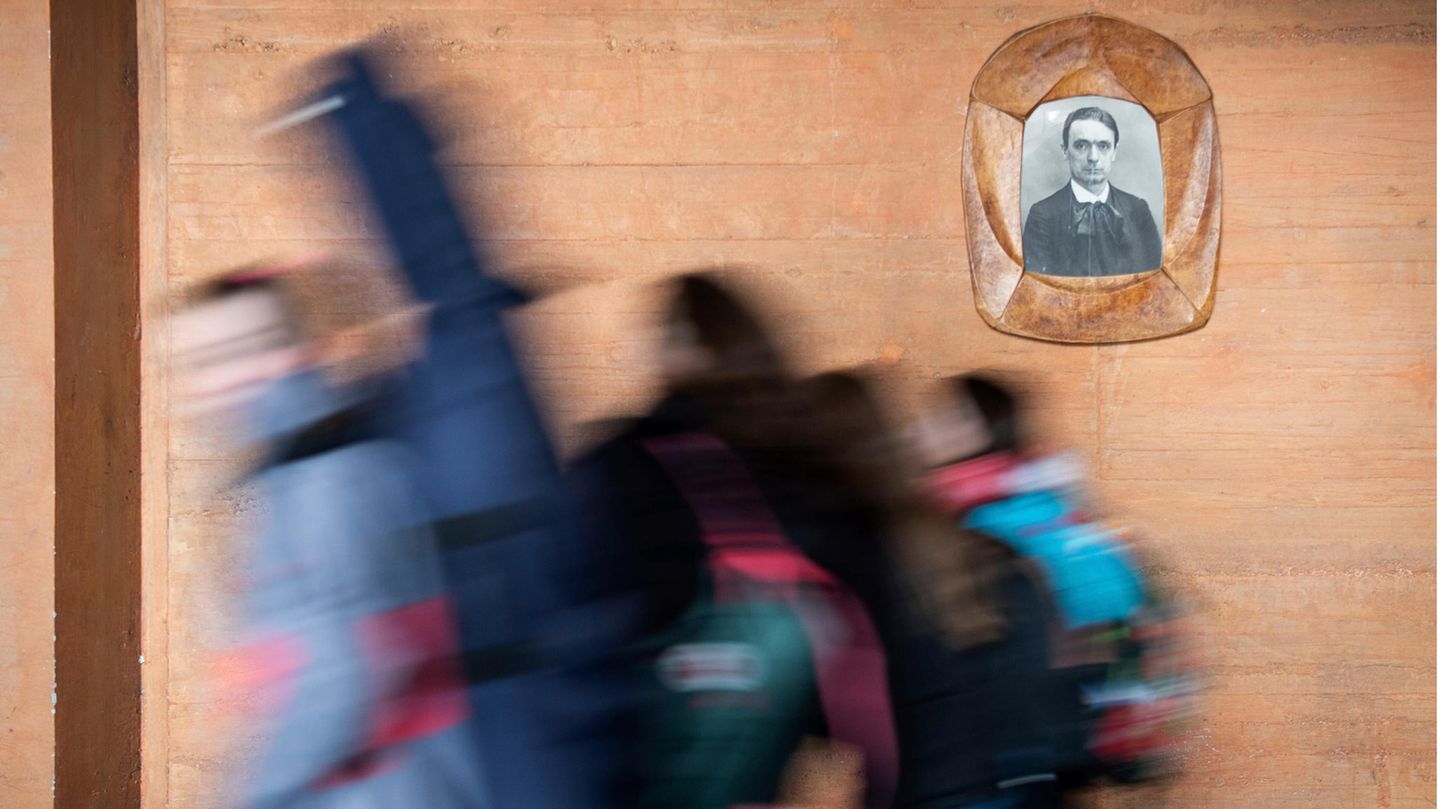 Schüler einer Waldorfschule gehen an einem Bild von Rudolf Steiner vorbei