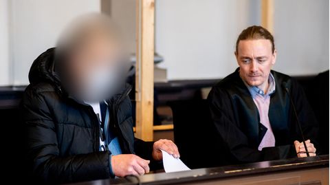 Ein wegen zweifachen Mordes und versuchten Mordes angeklagter Mann sitzt in einem Gerichtssaal neben seinem Verteidiger