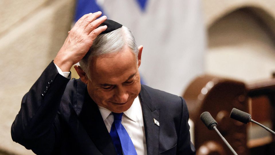 Ein älterer weißer Mann hält mit rechts seine schwarze Kippa auf dem weißen Haar
