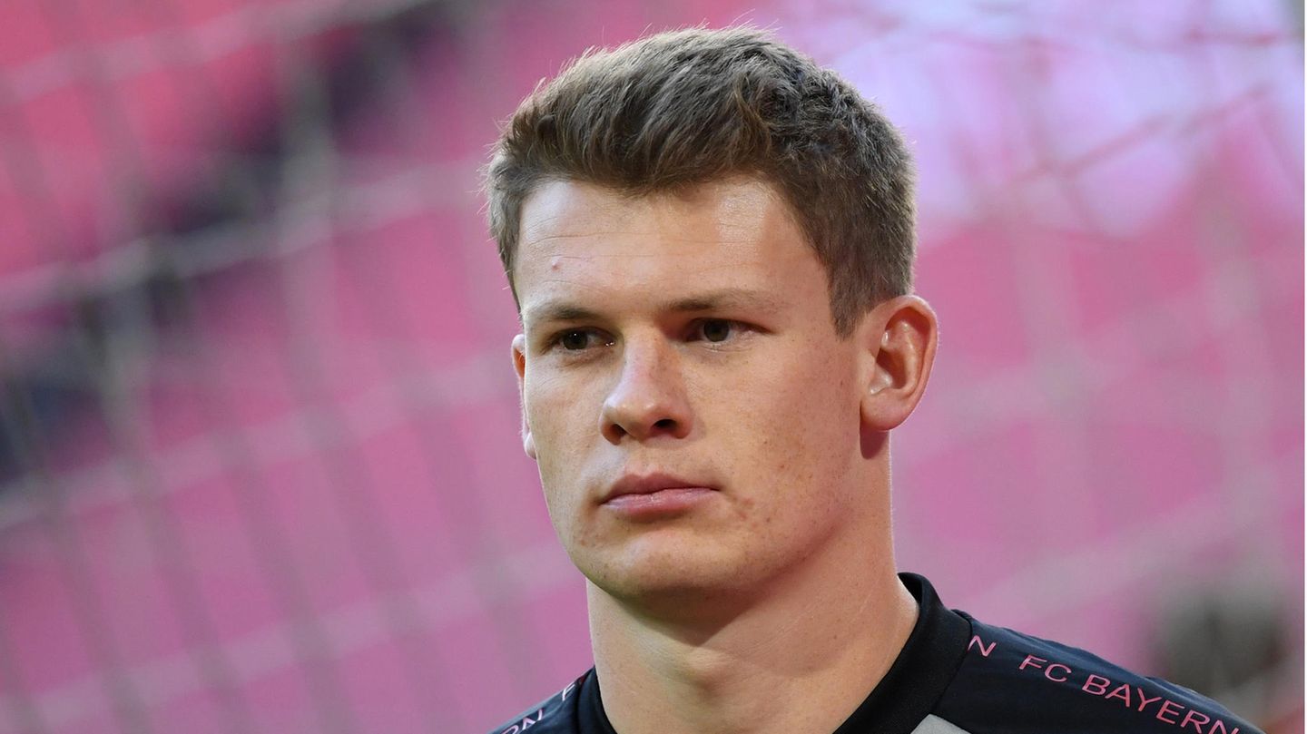 Ein junger weißer Mann mit kantigem Kinn und dunkelblondem Haar trägt ein Trikot mit "FC Bayern"-Print auf den Schultern