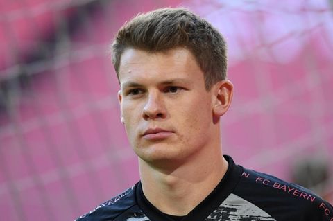 Ein junger weißer Mann mit kantigem Kinn und dunkelblondem Haar trägt ein Trikot mit "FC Bayern"-Print auf den Schultern