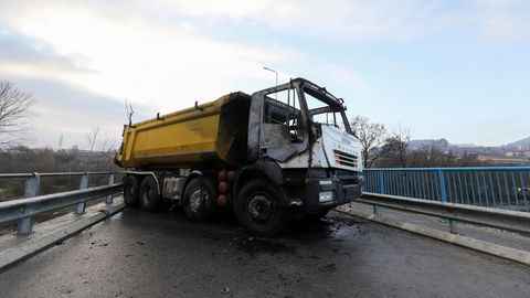 Ein ausgebrannter Lastwagen steht als Teil einer Barrikade auf einer Brücke
