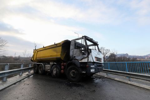 Ein ausgebrannter Lastwagen steht als Teil einer Barrikade auf einer Brücke