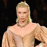 Dieses Modell führt in eine andere Epoche. Der große ovale Ausschnitt, die weit ausgestellten Ärmel, die hohen Stiefel: Die Inspiration lieferte sichtlich die Mode des 17. Jahrhunderts. 