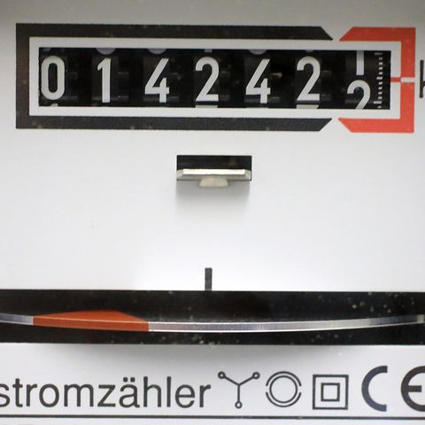Ein Stromzähler zeigt oben 014242,1 kWh an, unten dreht sich ein silbernes Rad mit roter Markierung