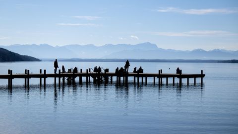 Menschen genießen das schöne Wetter auf einem Steg am Starnberger See