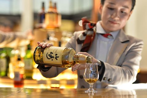 Eine Bardame schenkt Whisky aus einer Yamazaki-Flasche aus