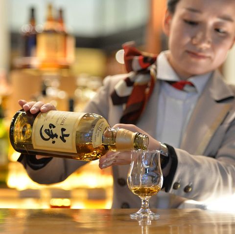 Eine Bardame schenkt Whisky aus einer Yamazaki-Flasche aus