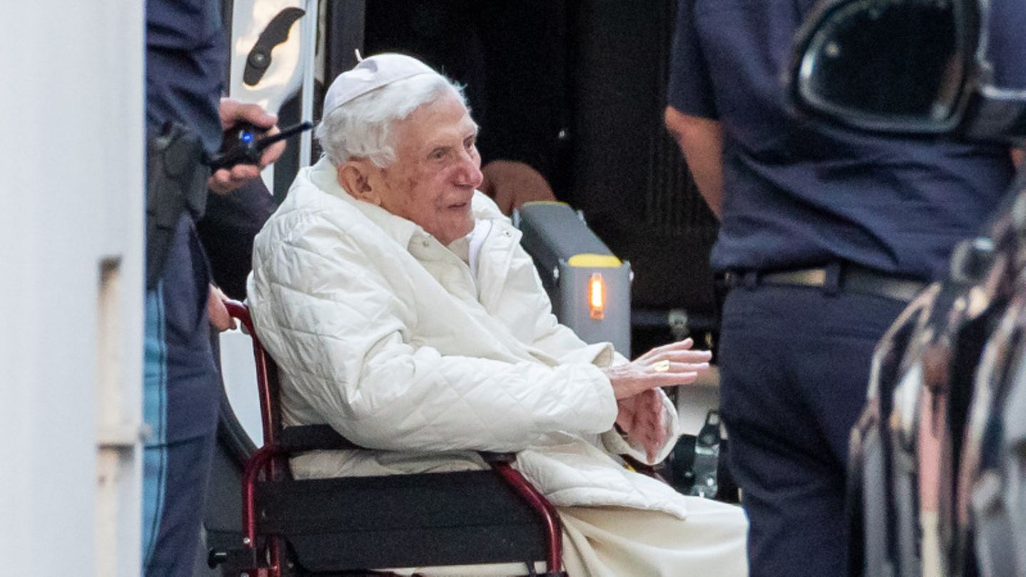 Der emeritierte Papst Benedikt XVI wird mit einem Rollstuhl in einen Bus geschoben. Er ist zum ersten Mal seit seinem Rücktritt vor mehr als sieben Jahren nach Deutschland zurückgekehrt. Der gebürtige Bayer besuchte seinen kranken Bruder.
