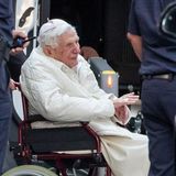 Der emeritierte Papst Benedikt XVI wird mit einem Rollstuhl in einen Bus geschoben. Er ist zum ersten Mal seit seinem Rücktritt vor mehr als sieben Jahren nach Deutschland zurückgekehrt. Der gebürtige Bayer besuchte seinen kranken Bruder.