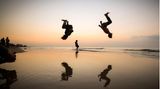 Gaza-Stadt, Gazastreifen. Palästinensische Kinder vollführen bei Sonnenuntergang akrobatische Einlagen am Ufer des Mittelmeers.