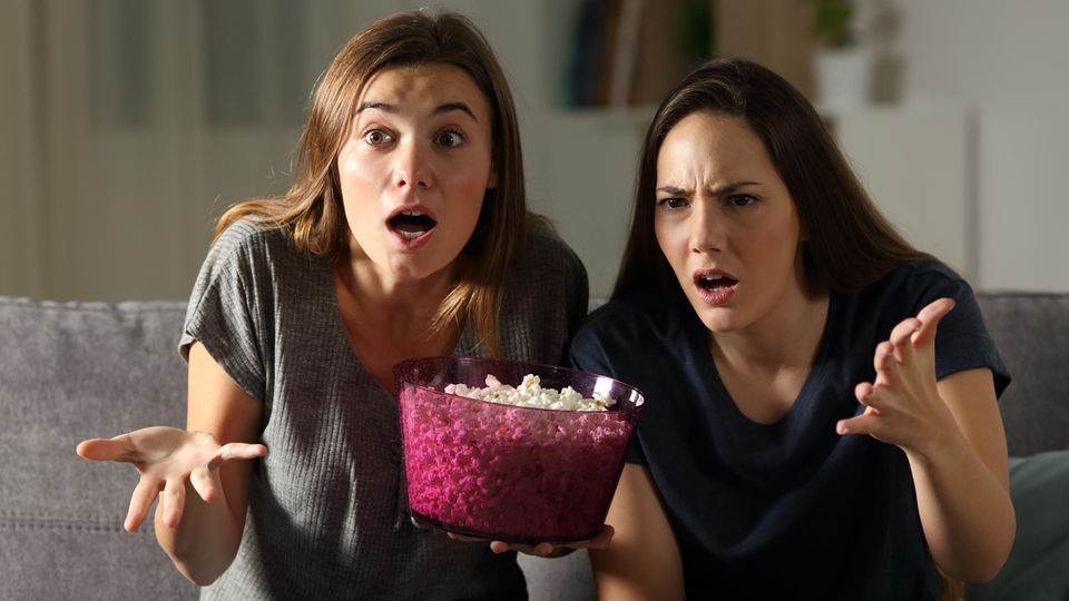 Frauen schauen schockiert auf einen Fernseher