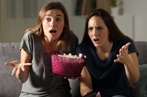 Frauen schauen schockiert auf einen Fernseher