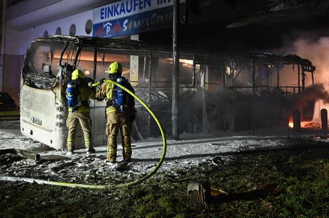 Feuerwehrmänner löschen an der Sonnenallee einen Reisebus, der von Unbekannten angezündet worden war.