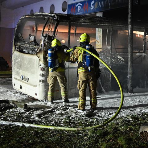 Feuerwehrmänner löschen an der Sonnenallee einen Reisebus, der von Unbekannten angezündet worden war.