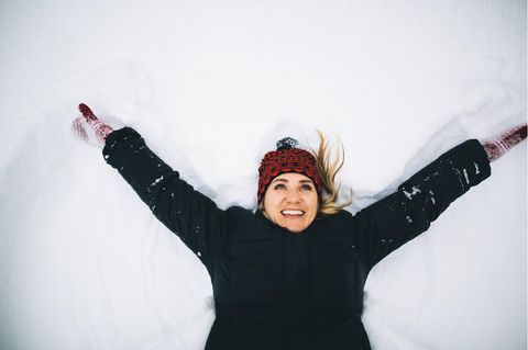 Bebilderung Neuanfang: Eine Frau liegt lachend im Schnee