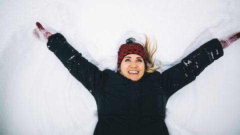 Eine Frau liegt lachend im Schnee