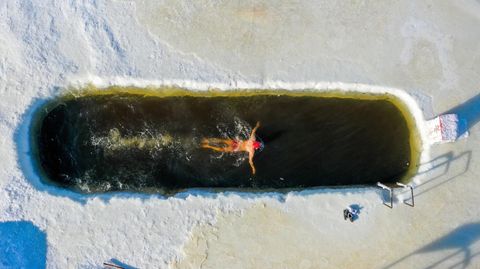Eisschwimmer zieht seine Bahnen im zugefrorenen Fluss Yimin