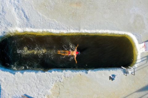 Eisschwimmer zieht seine Bahnen im zugefrorenen Fluss Yimin