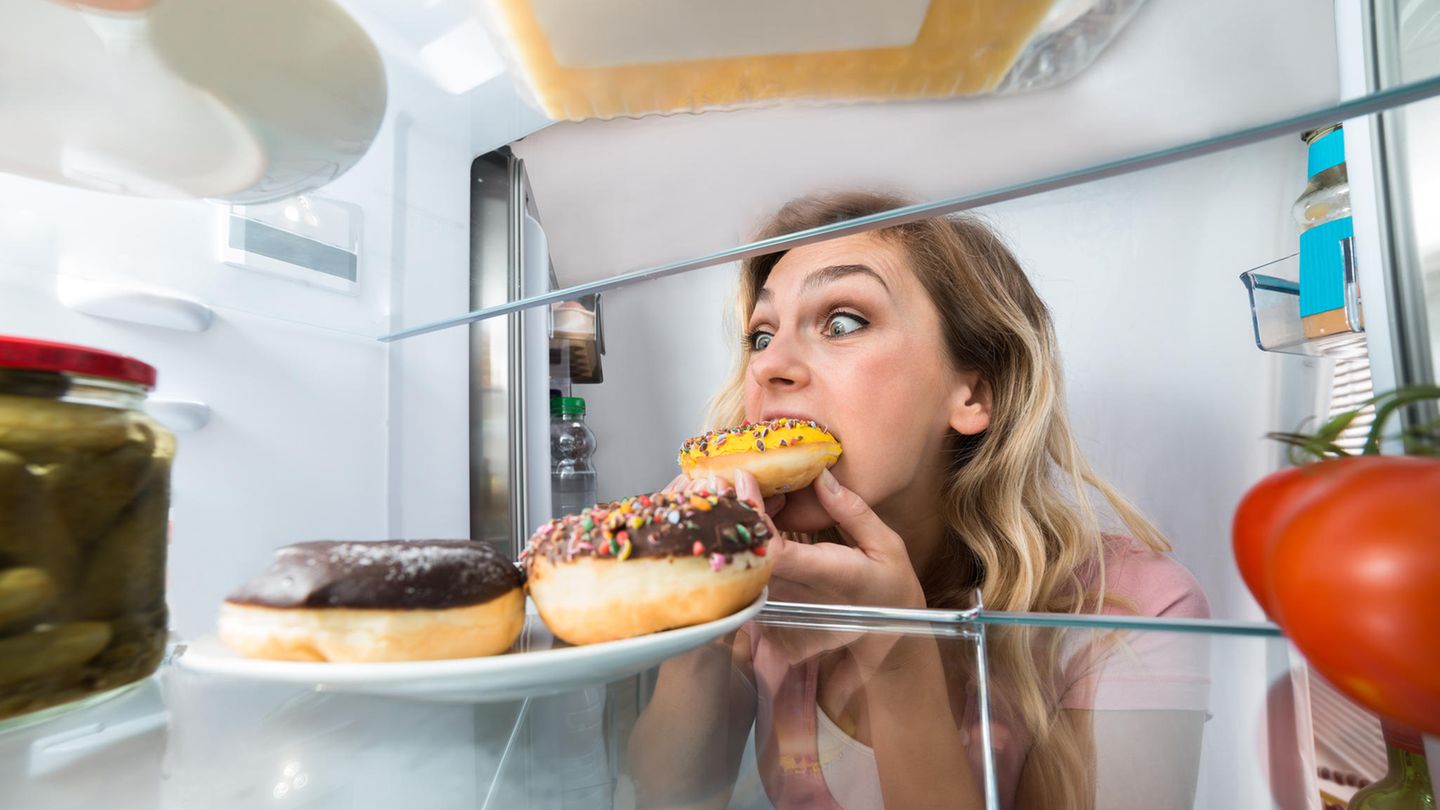 Eine Frau beißt in einen Donut Eine Frau beißt in einen Donut