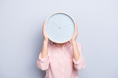 Eine Frau hält sich eine Uhr vors Gesicht