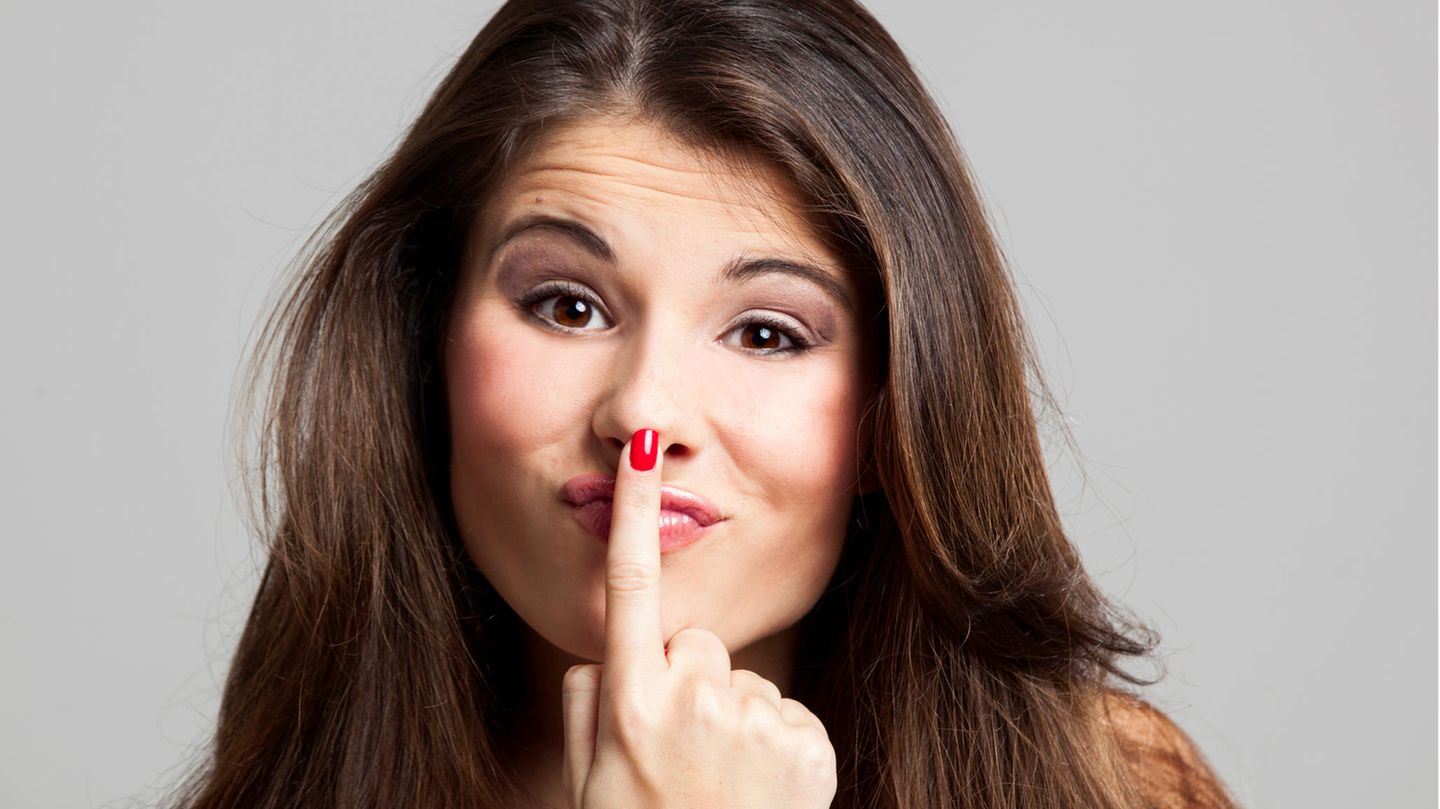 Eine Frau drückt sich mit dem Finger die Nase platt