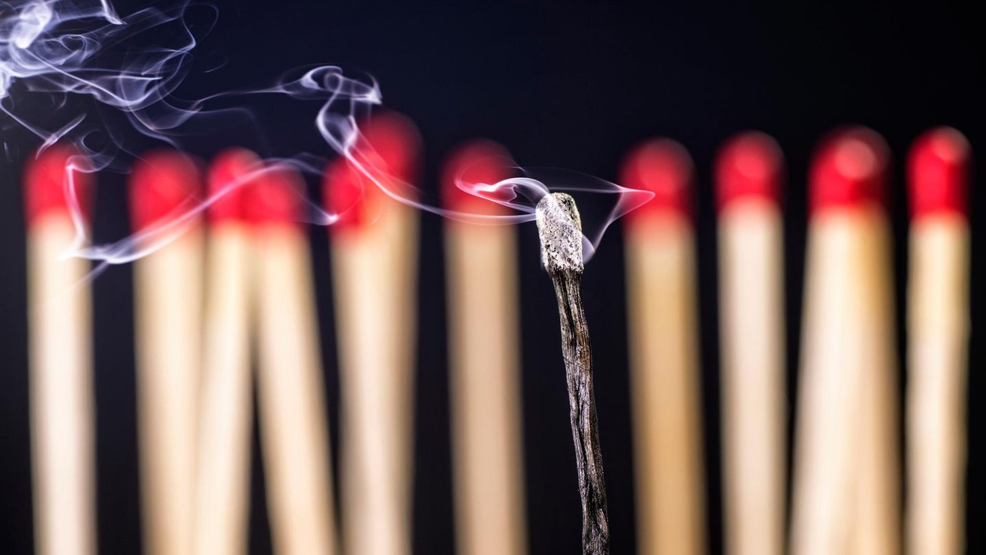 Burnout-Symbolbild: Mehrere unangezündete Streichhölzer in einer Reihe im Hintergrund, im Vordergrund ein abgebranntes