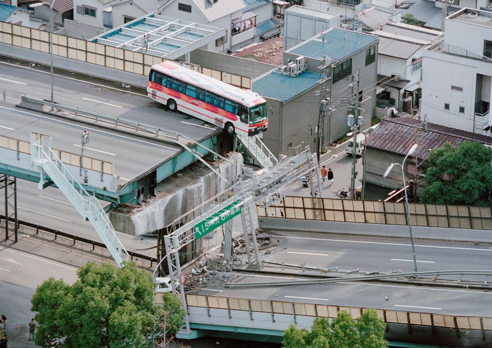 In der Stadt Nishinomiya, nur wenige Kilometer von Kobe entfernt, hängt ein Reisebus auf der Hanshin-Stadtautobahn rund 15 Meter über dem Abgrund, nachdem das Erdbeben die Fahrbahn zerstörte