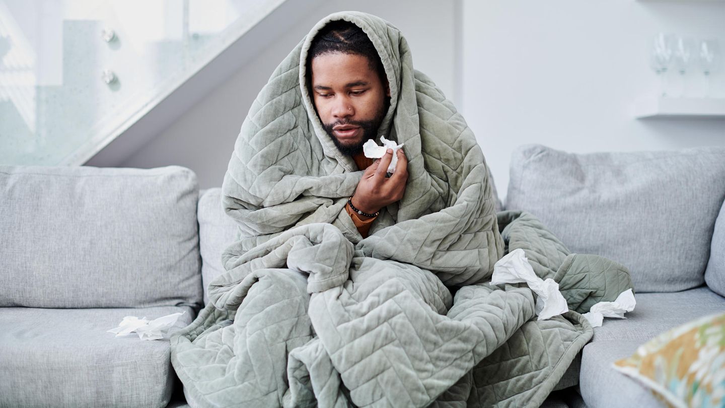 Ein kranker Mann sitzt auf dem Sofa