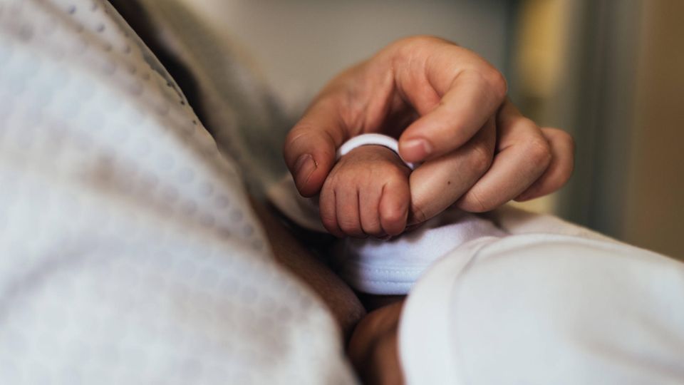Eine Frau hält die Hand eines neugeborenen Babys