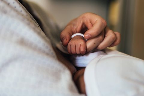 Eine Frau hält die Hand eines neugeborenen Babys