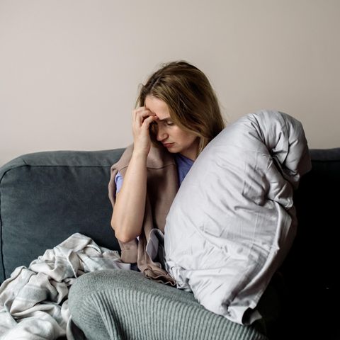 Autoimmunerkrankung: Eine Frau sitzt erschöpft auf dem Sofa
