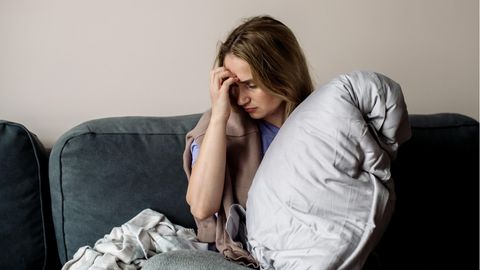 Autoimmunerkrankung: Eine Frau sitzt erschöpft auf dem Sofa