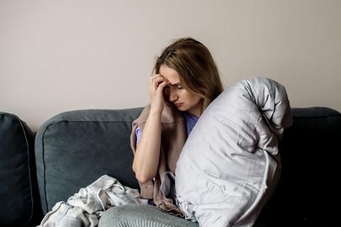 Autoimmunerkrankung: Eine Frau sitzt erschöpft auf dem Sofa