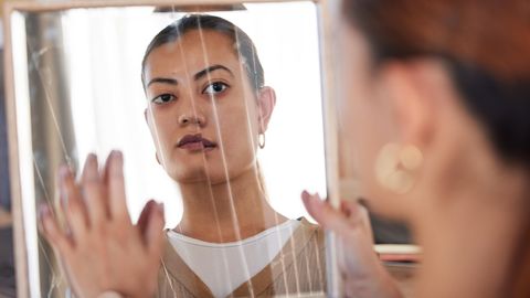 Autoimmunerkrankung: Frau sieht sich im zersplitterten Spiegel an