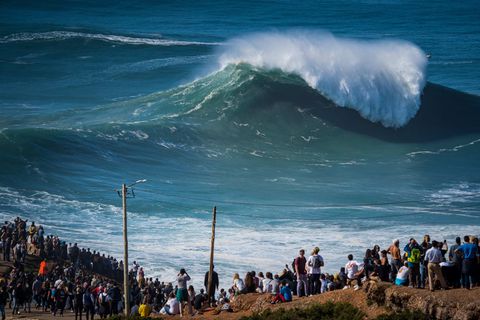 Menschen beobachten die ersten großen Wellen der Wintersaison am berühmten Surfer-Strand Praia do Norte