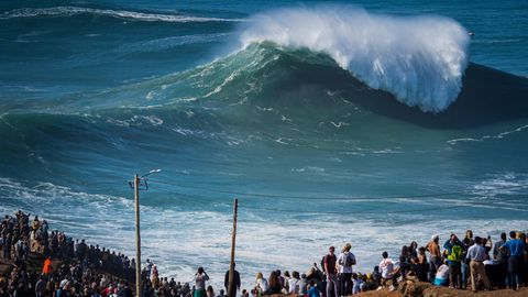 Menschen beobachten die ersten großen Wellen der Wintersaison am berühmten Surfer-Strand Praia do Norte