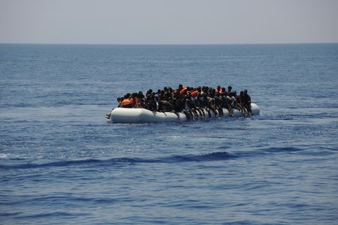 Migranten sitzen eng an eng auf einem Schlauchboot auf dem Mittelmeer