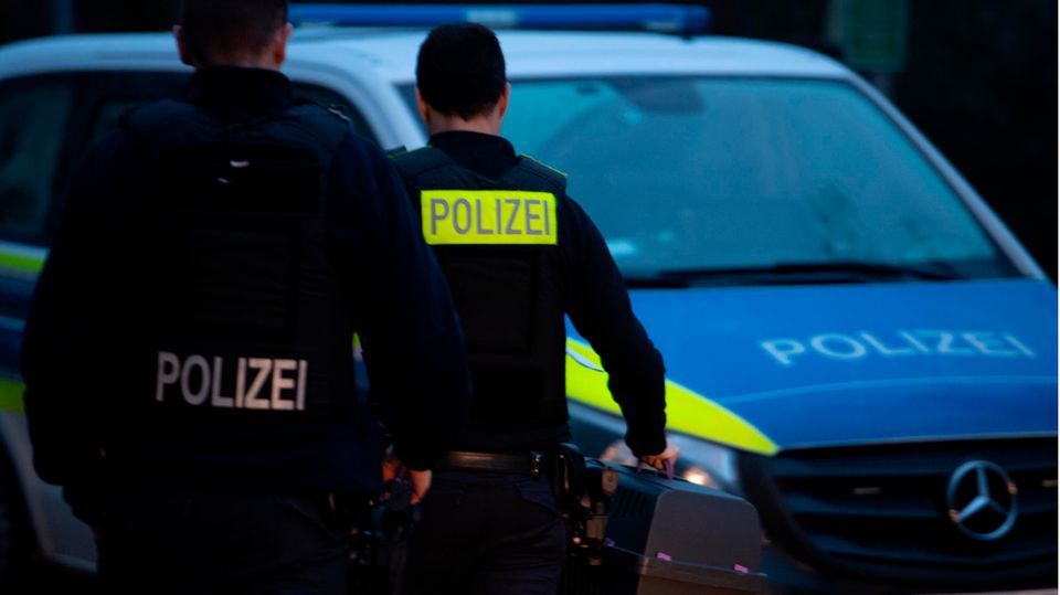 Polizeibeamte gehen mit einer Hundetransportbox in Berlin-Lichtenberg zu einem Fahrzeug