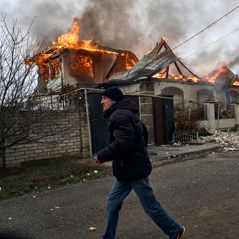 Cherson, Ukraine: A resident runs past a burning house