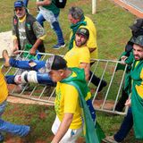 Ein verletzter Angreifer wird von anderen Bolsonaro-Anhängern auf einem Absperrgitter davongetragen