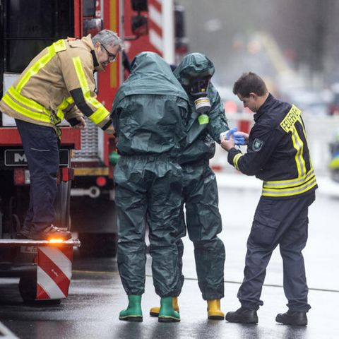 Spezialkräfte der Feuerwehr in Schutzanzügen kommen von ihrem Einsatz