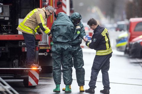Spezialkräfte der Feuerwehr in Schutzanzügen kommen von ihrem Einsatz