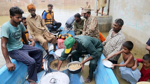 Vor der Flut gerettete Pakistaner sitzen auf einem Boot