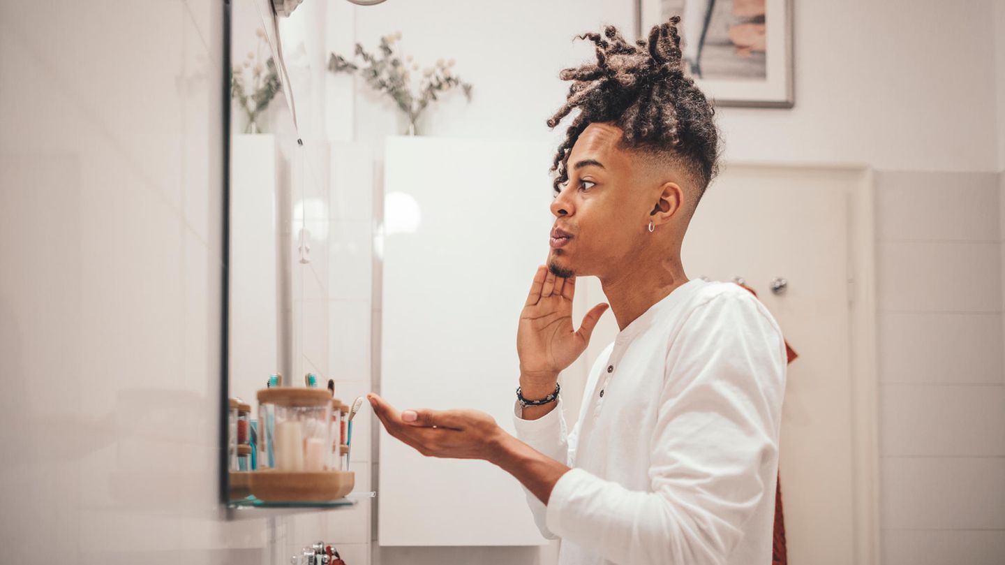 Person bei der Gesichtsreinigung vor dem Spiegel