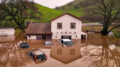In Kalifornien ragen vor einem Haus vier Autos aus den Überschwemmungen