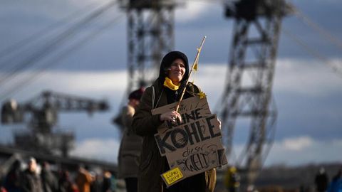 Eine Aktivistin trägt in Lützerath ein Schild mit der Aufschrift "Für keine Kohle der Welt"