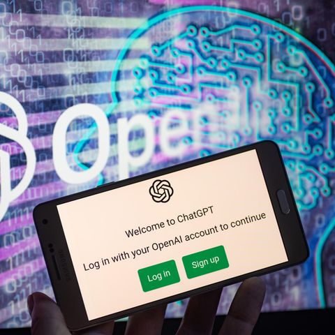 Ein Smartphone mit dem geöffneten Chatbot ChatGPT, im Hintergrund das Logo "Open AI"