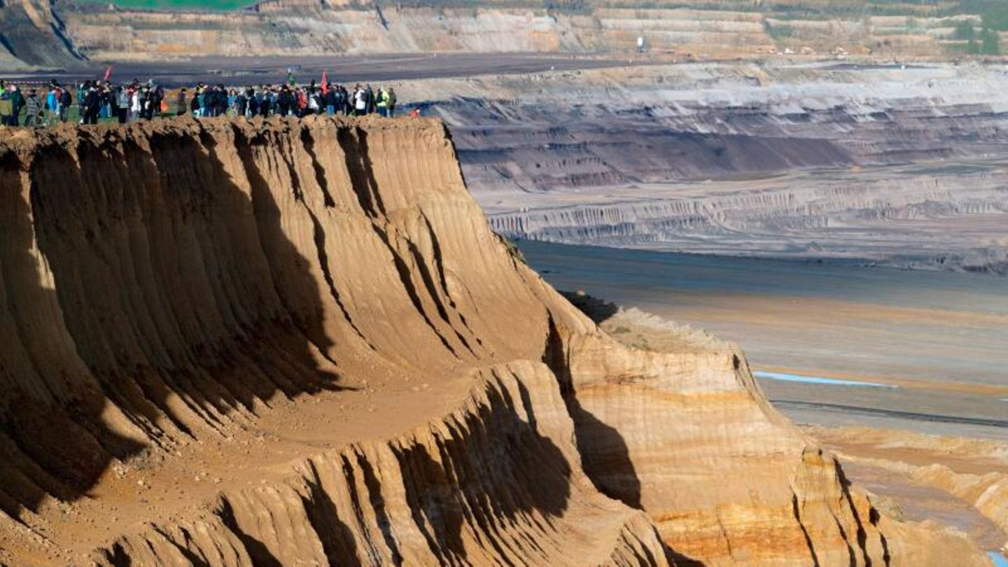 Demonstranten in Lützerath stehen an der Kante des Tagebaus Garzweiler II